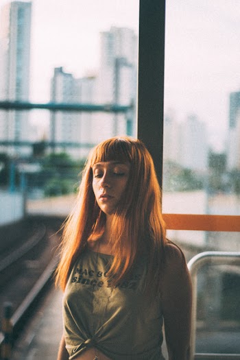 Woman Wearing Gray Tank Top Standing in Front of Glass Panel