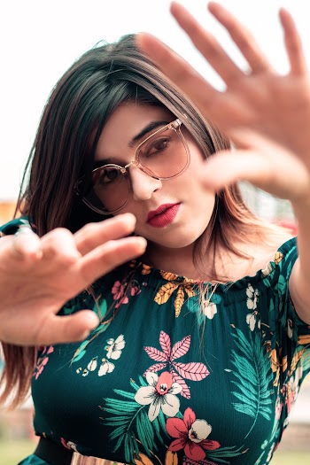 Woman Wearing Green and Multicolored Floral Blouse Standing While Raising Both Hands