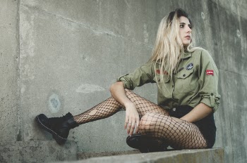 Woman Wearing Green Button-up Shirt Sitting on Grey Concrete Surface