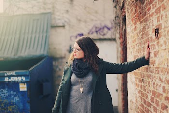 Woman Wearing Green Coat Leaning Left Hand on Wall