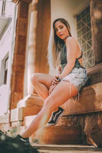 Woman Wearing Green Halter-strap Top and Blue Denim Shorts Leaning on Wall