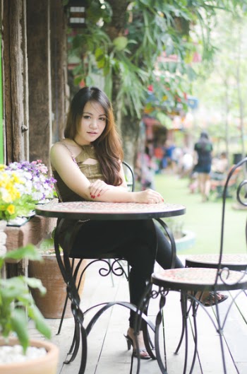 Woman Wearing Green Halter-top Blouse and Black Leggings Outfit Sitting on Black Metal Chair