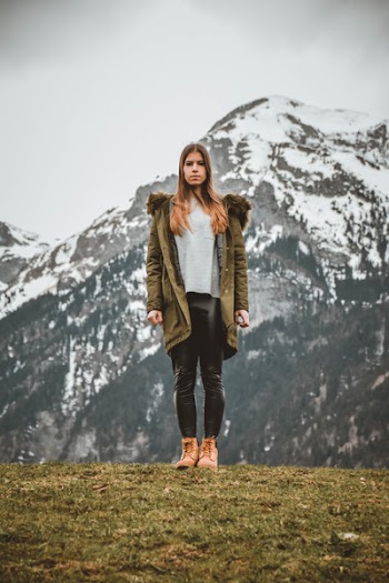 Woman Wearing Green Jacket in Front of Snowy Mountain