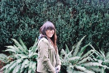 Woman Wearing Green Jacket Standing Next Boston Fern Plant