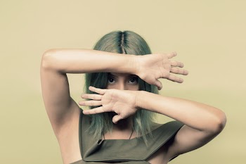 Woman Wearing Green Sleeveless Top Covering Her Face but Eyes With Both Hands