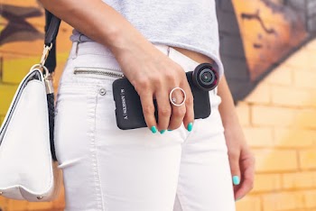Woman Wearing Grey Shirt And White Denim Jeans Holding Black Smartphone