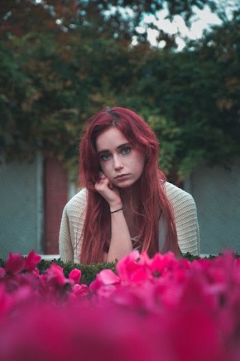 woman wearing grey shirt near pink petaled flowers during daytime