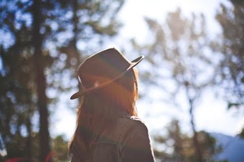 woman wearing hat standing facing tree