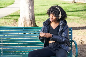 woman wearing headphones choosing song in park on a fall day