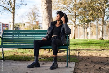 woman wearing headphones sitting on park bench on a fall day