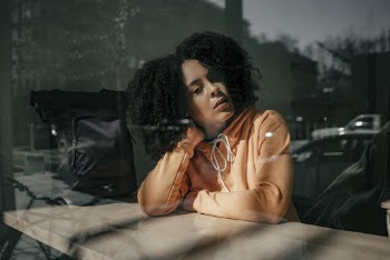 Woman Wearing Hoodie Leaning on Desk