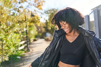 woman wearing jacket dancing in park on a fall day looking to side
