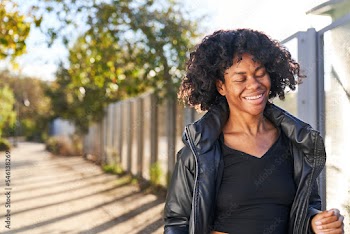 woman wearing jacket dancing in park on a fall day smiling with eyes closed