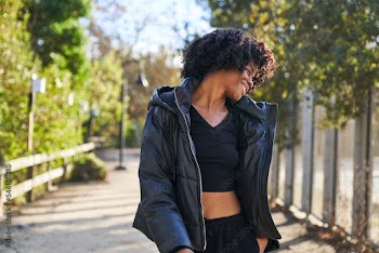 woman wearing jacket dancing in park on a fall day smiling with head turned