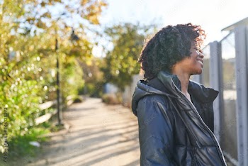 woman wearing jacket dancing in park on a fall day turning away