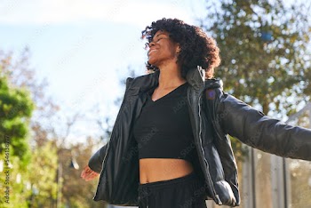 woman wearing jacket dancing in park on a fall day with arms open