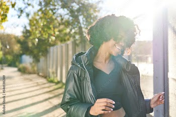 woman wearing jacket dancing in park on a fall day with sunlight