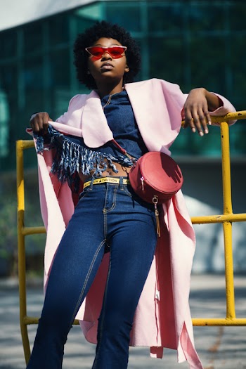Woman Wearing Jeans Leaning on Yellow Metal Bar
