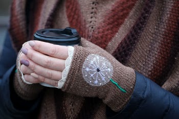 Woman wearing knitted gloves holding a cup of coffee