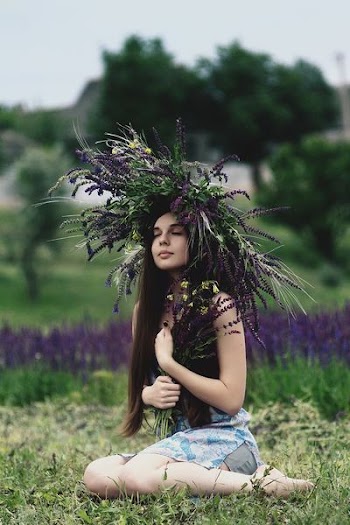 woman wearing lavender headdress sitting on grass
