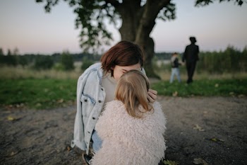 Woman Wearing Light-blue Denim Jacket Kissing Girl Wearing White Coat