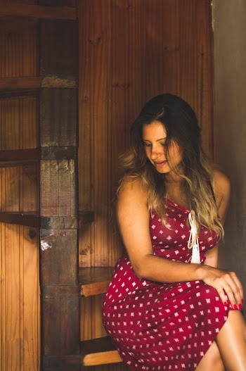Woman Wearing Maroon and White Polka-dot Dress Sitting on Brown Wooden Spiral Stair