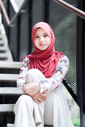 Woman Wearing Maroon Hijab and Floral Top Sitting on Stairs