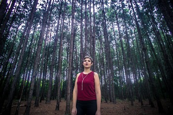 Woman Wearing Maroon Tank Top and Black Bottoms Surrounded With Brown Trees