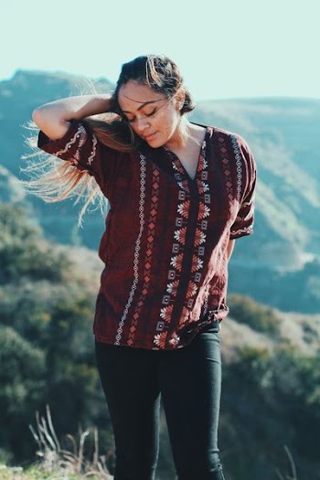 woman wearing maroon top standing on mountain peak