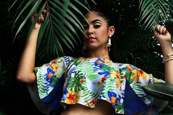 woman wearing multicolored floral crop-top holding green palm leaves