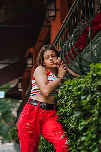 Woman Wearing Multicolored Striped Crop Top Leaning on Safety Rail