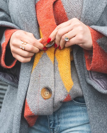 Woman Wearing Multicolored Sweater and Holding Its Buttons