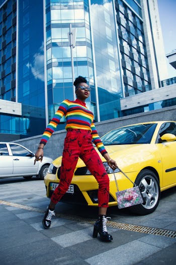 Woman Wearing Multicolored Sweater and Red Denim Jeans Near Yellow Vehicle