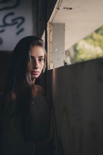 Woman Wearing Off Shoulder Blouse Leaning on Concrete Wall