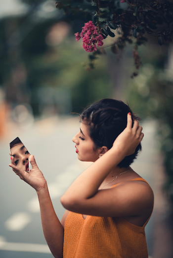 Woman Wearing Orange Cami Top Holding Mirror