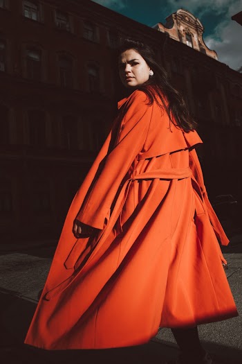 Woman Wearing Orange Jacket With Belt Standing Outdoor Near the Building