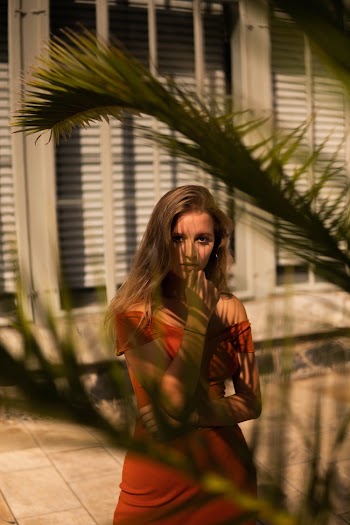 Woman Wearing Orange Off-shoulder Top Standing Near Palm Tree during Sunny Day
