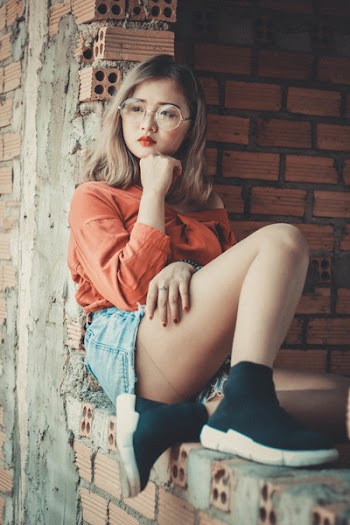 Woman Wearing Orange Scoop-neck Long-sleeved Top and Blue Denim Mini Shorts