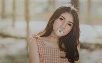 Woman Wearing Orange Sleeveless Dress Bites White Petaled Flower