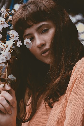 Woman Wearing Orange Sweat Shirt Holding White Flowers
