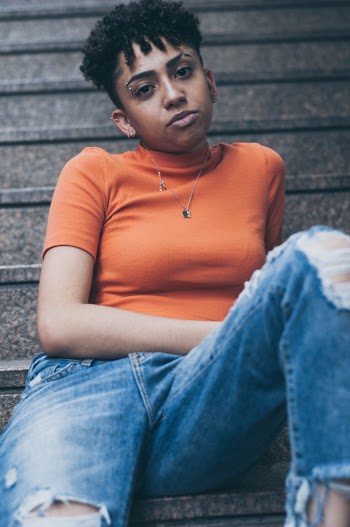 Woman Wearing Orange Turtleneck Top And Blue Ripped Jeans