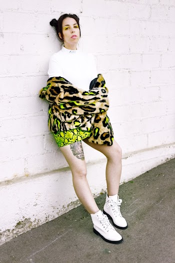 Woman Wearing Pair Of White Shoes Leaning On White Wall