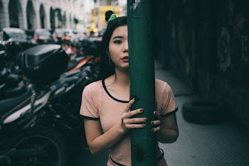 Woman Wearing Pink and Black Rim Crew-neck Shirt Standing Behind A Steel Post