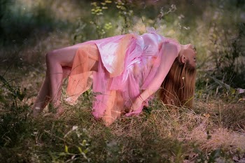 Woman Wearing Pink and Orange Dress While Lying on Grass Field