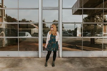 woman wearing pink bolero and black leggings standing in front of glass wall