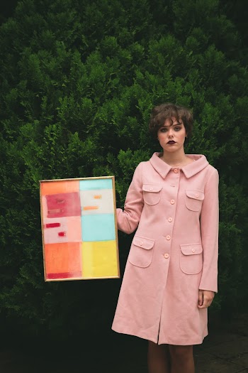 Woman Wearing Pink Button-up Coat Holding Photo Frame With Artwork