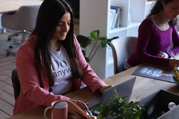 Woman Wearing Pink Coat Sitting On Chair While Using Laptop