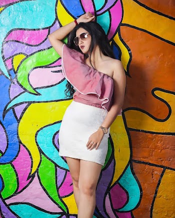 Woman Wearing Pink Off Shoulder Blouse and White Skirt Leaning on Graffiti Wall
