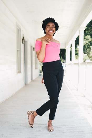 Woman Wearing Pink Off-shoulder Shirt and Black Pants While Standing Near Wall