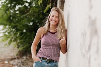 woman wearing pink sleeveless top leaning on wall